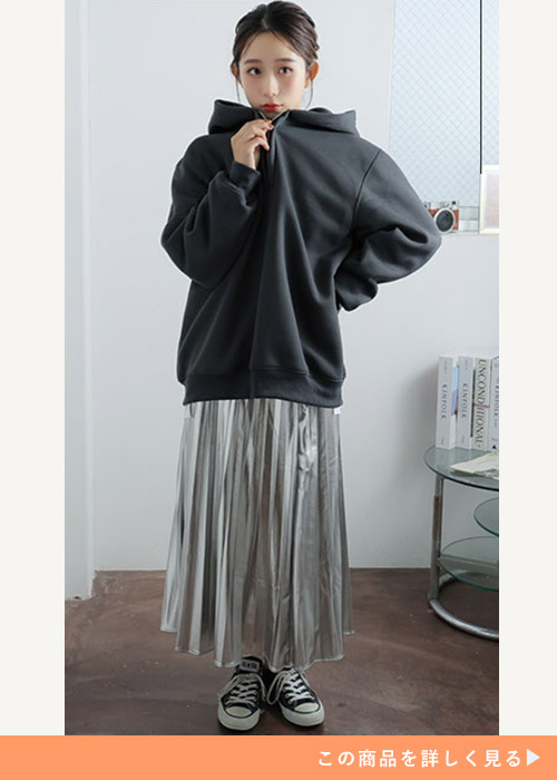 ブラックのハーフジップパーカとシルバーのプリーツスカートのコーデにスニーカーを履く女性