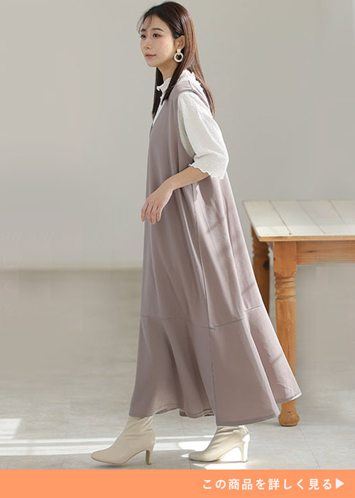 白トップス×グレージュのジャンパースカートを着る女性