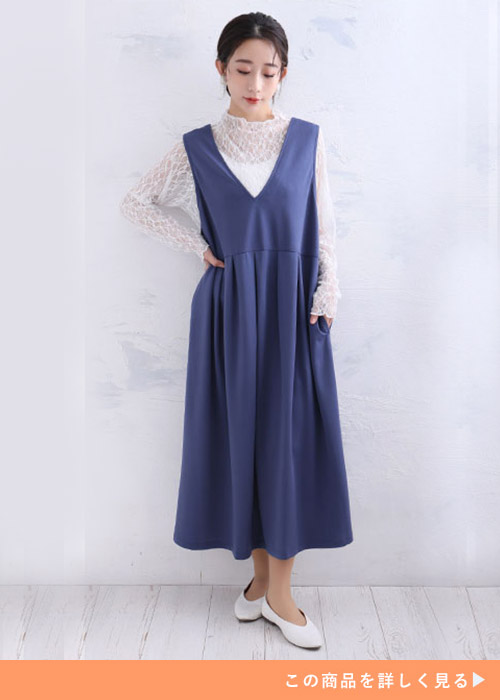 白のレーストップス×くすみブルーのジャンパースカートを着る女性