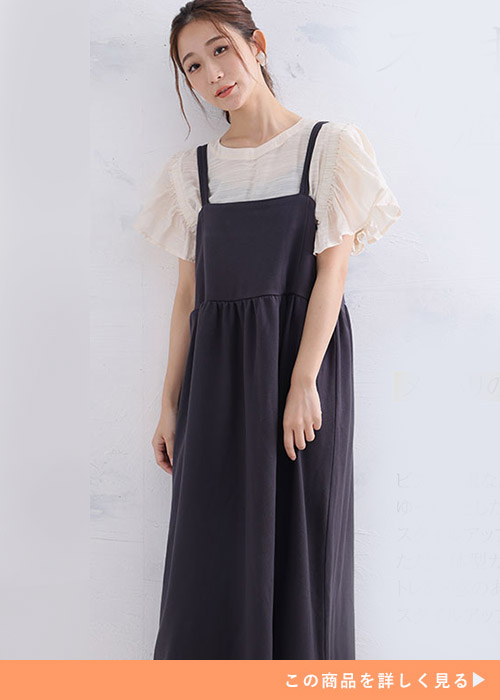 ピンクベージュのフリル袖ブラウス×チャコールのビスチェ風ジャンパースカートを着る女性