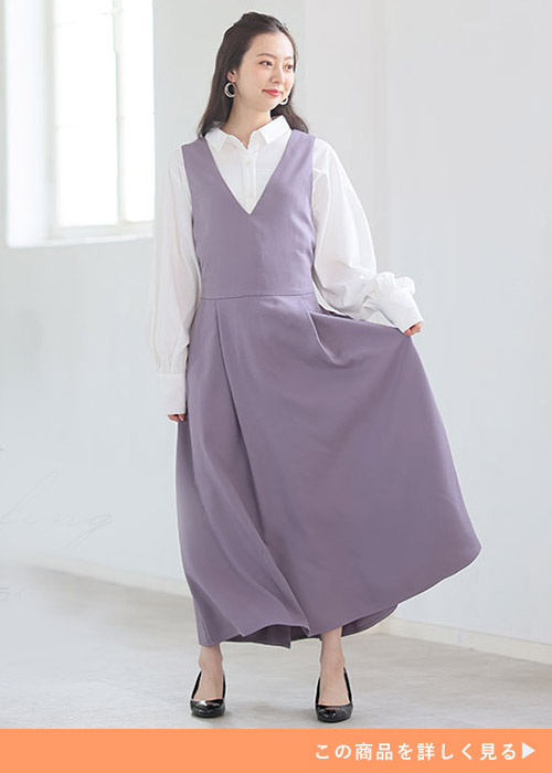 白のシャツ×ライラック色のジャンパースカートを着る女性