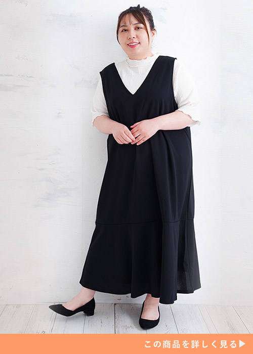 白のリブトップス×黒のジャンパースカートを着る女性