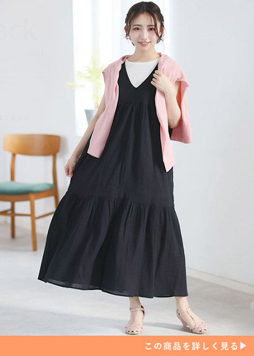 白のノースリトップス×黒ジャンスカを着て、ピンクトップスを肩掛けする女性