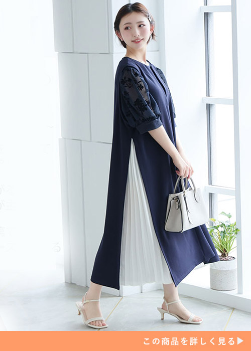 ネイビーのシアーブラウス×ネイビーのサイドプリーツ入りジャンパースカートを着る女性