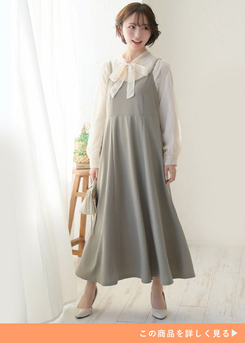アイボリーのリボンタイブラウス×ライトグリーンのジャンパースカートを着る女性