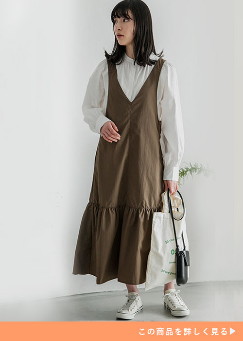 白のバンドカラーシャツ×ブラウンのジャンパースカートを着る女性