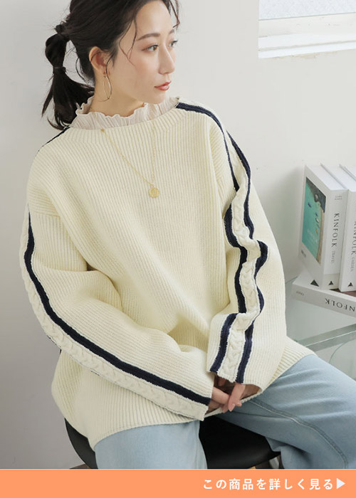 オフホワイト×ネイビーのニットにフリル襟トップスをレイヤードしデニムパンツを履く女性