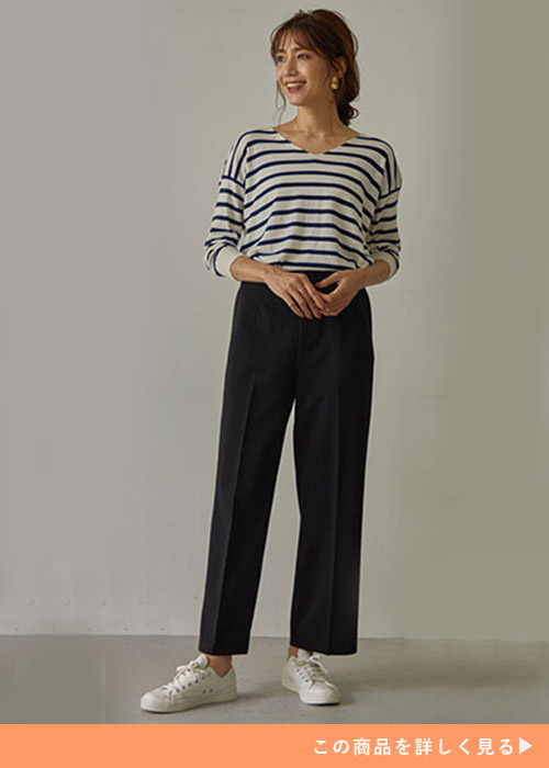 ブラックのワイドパンツとボーダーのトップスにホワイトスニーカーを履く女性