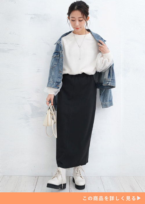 オフベージュのチュール袖トレーナーとブラックスカートのコーデに、デニムジャケットを羽織る女性