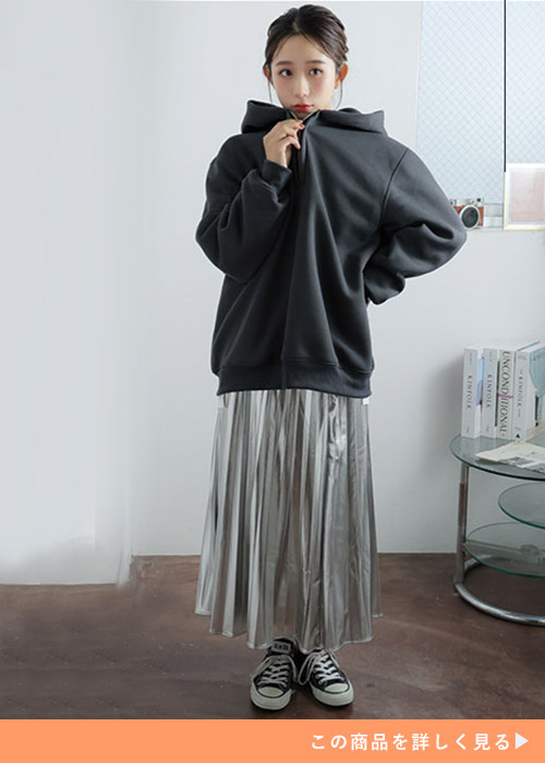 ブラックの裏起毛パーカとシャイニープリーツスカートのコーデにスニーカーを履く女性