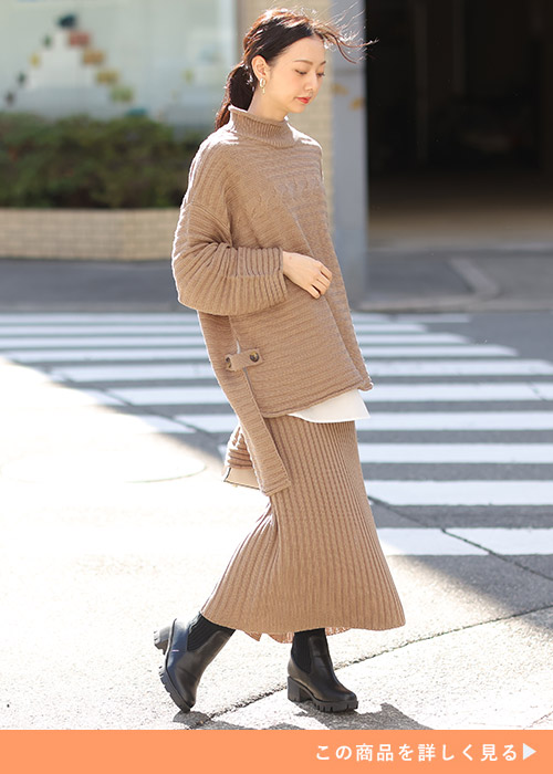 ベージュのニットセットアップのコーデにブラックのサイドゴアブーツを履く女性
