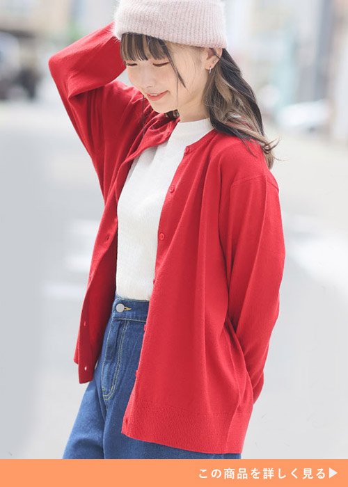 ホワイトトップスとデニムパンツのコーデにレッドカーディガンを羽織る女性