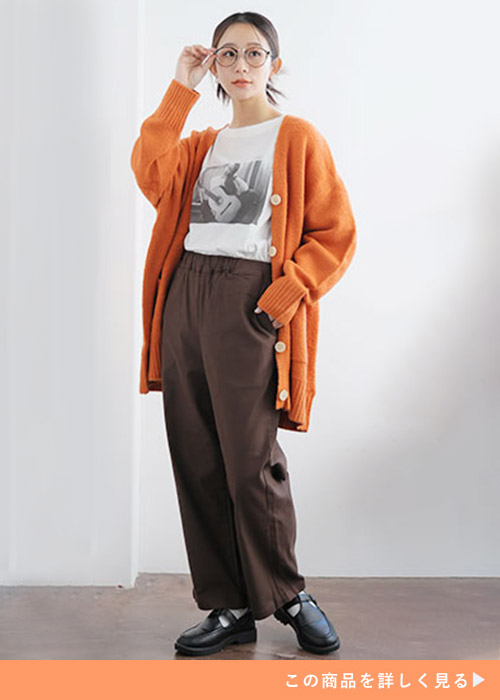 白Tシャツ×茶のワイドパンツにオレンジのカーディガンを羽織る女性