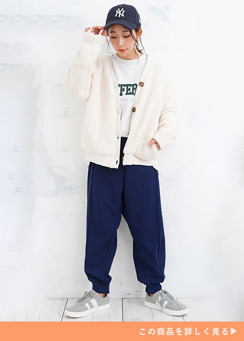 グレーのスウェットトップス×ネイビーのジョガーパンツに白のボアカーディガンを羽織る女性