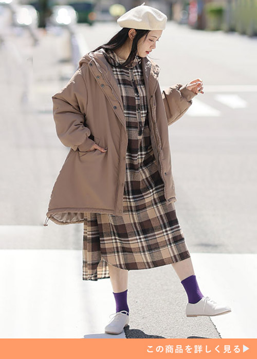 ブラウンのチェック柄ワンピースにブラウンのアウターを羽織る女性