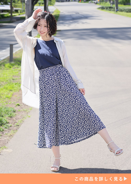 ブルーのタンクトップ×ネイビーの花柄ワイドパンツに、アイボリーのシアーシャツを羽織る女性