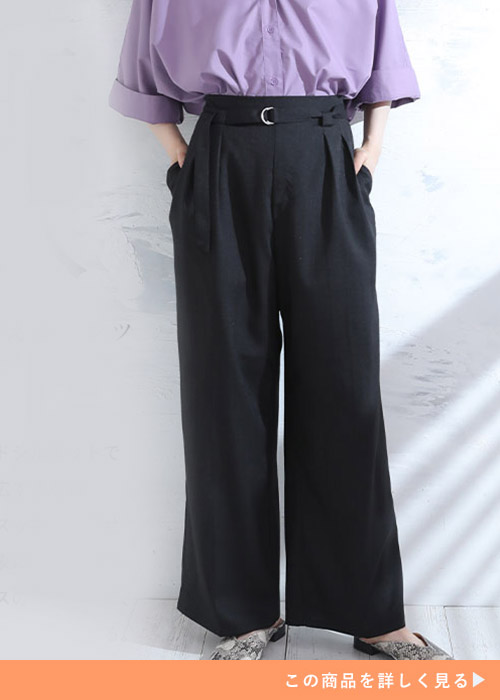 センタープレスとタックの入った、黒のベルト付きワイドパンツを履く女性