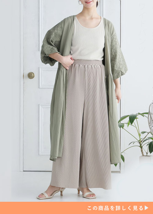 アイボリーのトップス×ベージュのプリーツワイドパンツに、くすみグリーンのロングカーディガンを羽織る女性