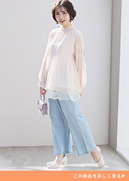 淡いピンク色のチュニックトップス×ライトブルーのデニムワイドパンツを着る女性