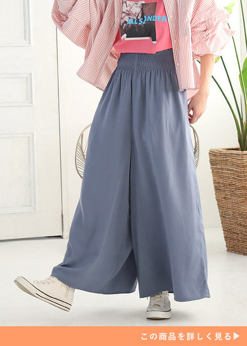 ピンクのTシャツ×ライトブルーのワイドパンツにストライプ柄シャツを羽織り、白スニーカーを履く女性