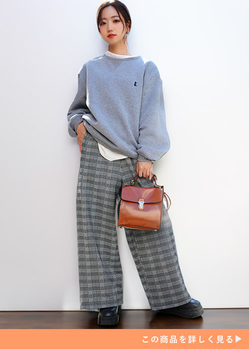 白トップスにグレーのスウェットを重ね着して、グレンチェック柄のワイドパンツを履く女性