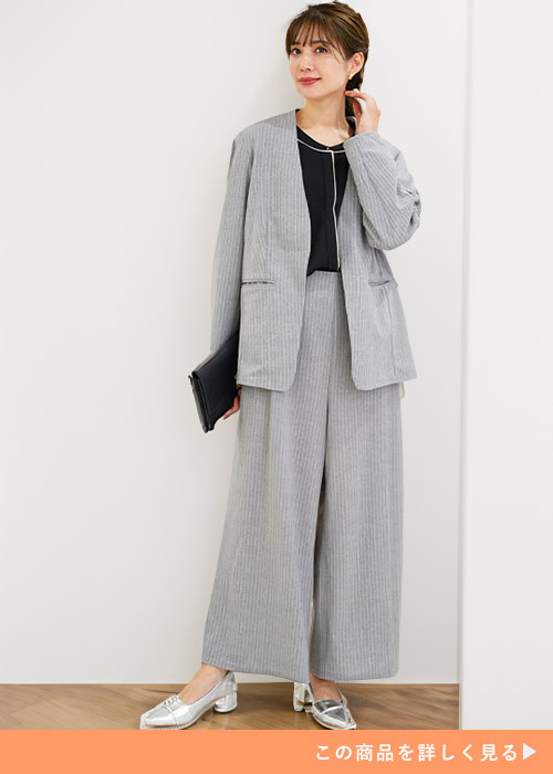 グレーのセットアップスーツ×黒ブラウスを着る女性