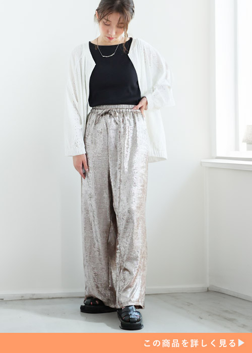 黒トップス×ブロンズのラメ入りワイドパンツに、カットワークレースの白ブルゾンを着る女性