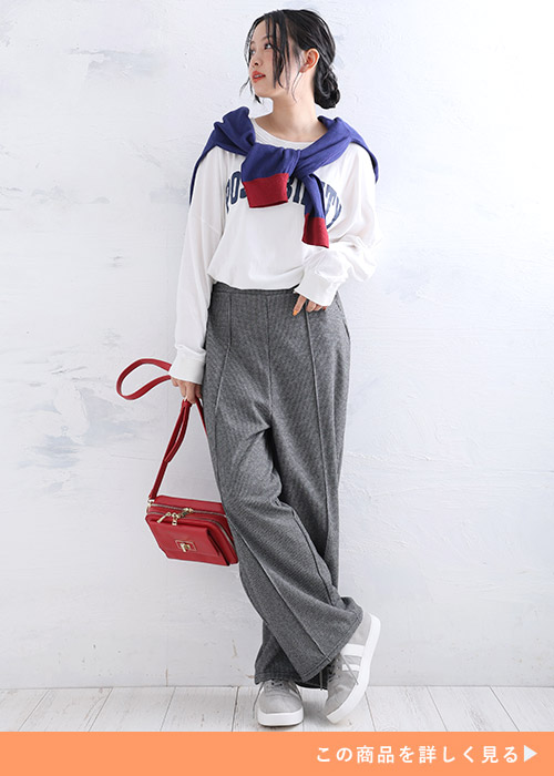 白のロゴT×千鳥柄ワイドパンツを着て、ブルー系のトップスを肩に巻く女性