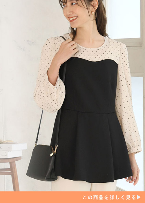 ベージュドットとブラックデザインのトップスとベージュボトムのコーデにブラックバッグを持つ女性