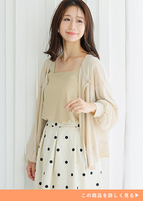 オフベージュとシャンパンカラーのカーディガンとタンクトップセットにドットスカートを履く女性