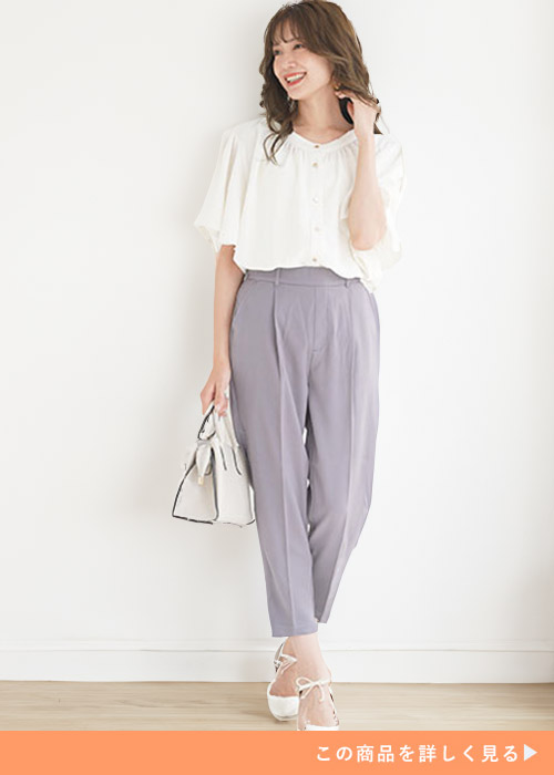 ライトグレーのテーパードパンツとホワイトブラウスのコーデにホワイトバッグを持つ女性