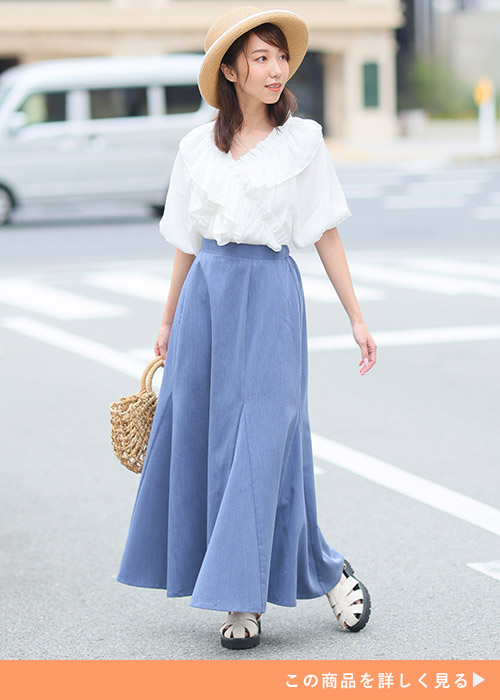 デニムブルーのマーメイドスカートとホワイトブラウスのコーデにかごバッグを合わせる女性