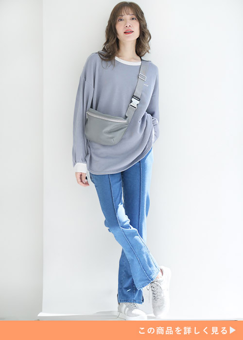 ブルーの美脚デニムパンツとグレーのトップスのコーデにホワイトスニーカーを履く女性