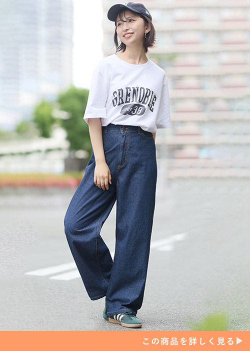 ネイビーのパンツとホワイトTシャツのコーデにキャップとスニーカーを合わせる女性