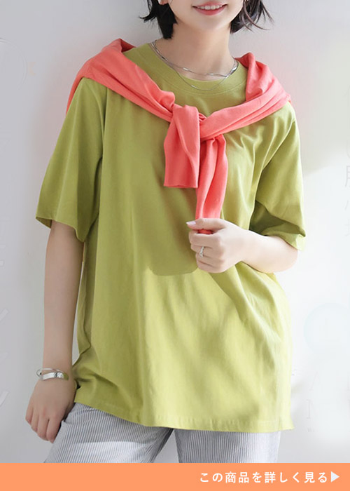 ピスタチオカラーのTシャツとストライプパンツのコーデに、サーモンピンクのカーデを羽織る女性