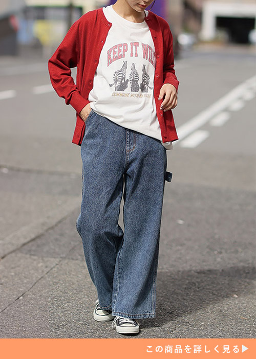 デニムペインターパンツとTシャツのコーデにレッドカーデを羽織る女性