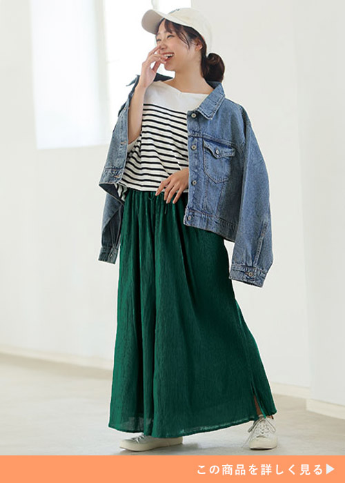 ダークグリーンのスカンツとボーダートップスのコーデにGジャンを羽織る女性