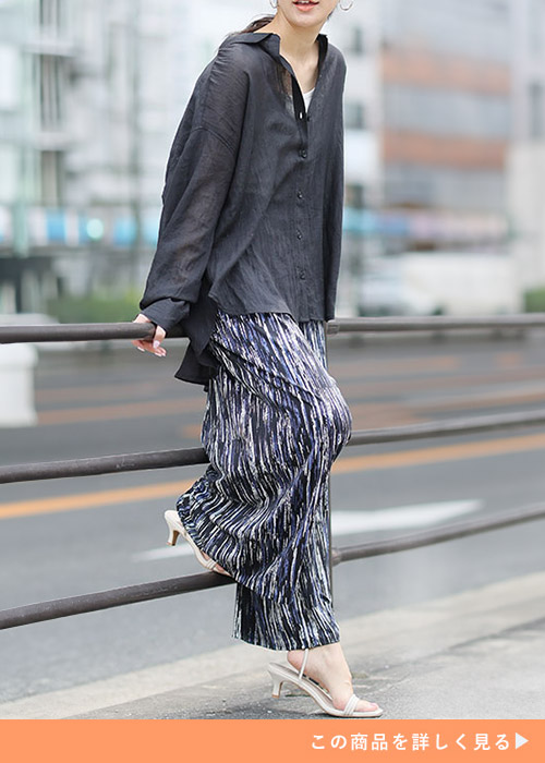 ブラックストライプのワイドパンツとブラックシャツのコーデにサンダルを履く女性