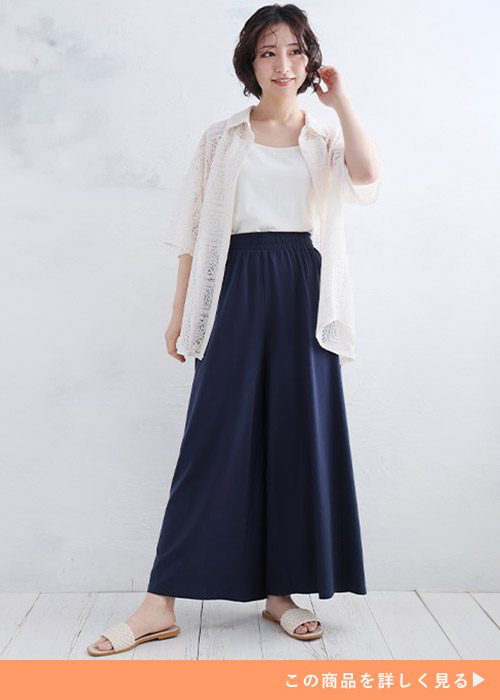 ネイビーのワイドパンツとホワイトトップスのコーデにレースシャツを羽織る女性