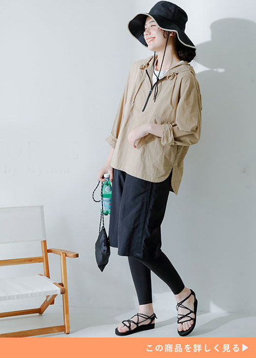 ベージュラッシュガードとレギンスとパンツのコーデにサンダルを履く女性