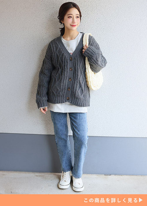 ホワイトトップスとデニムパンツのコーデにチャコールのケーブルニットを羽織る女性