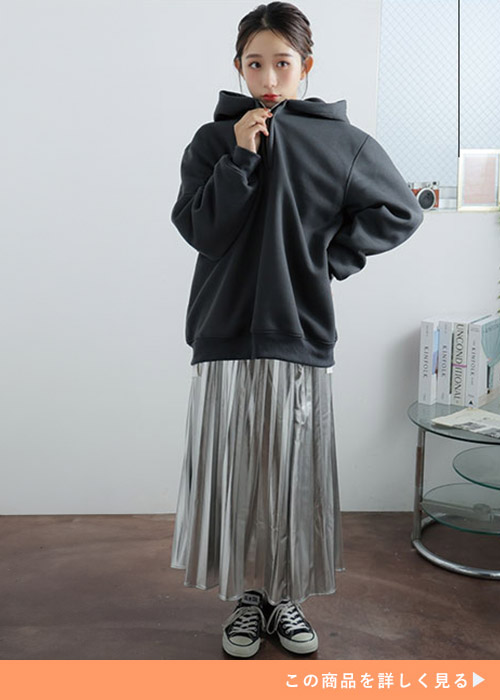 ブラックのハーフジップパーカとメタリックスカートのコーデにスニーカーを履く女性