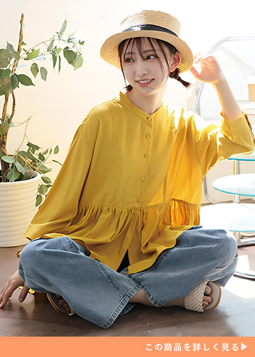 イエローのウエスト切り替えブラウスとデニムパンツのコーデにストローハットを合わせる女性