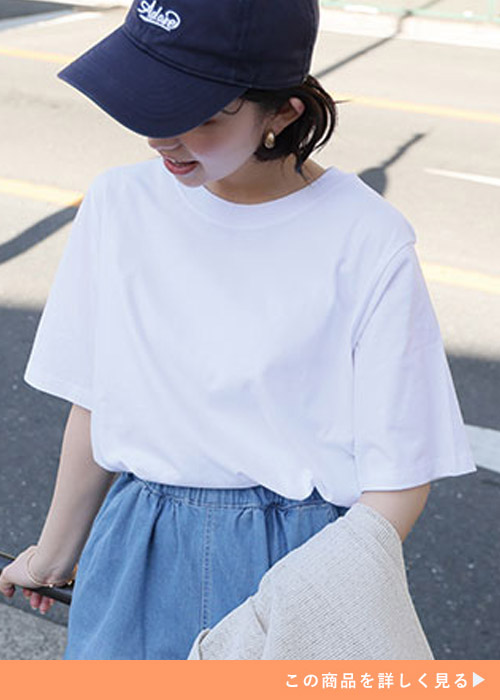 ホワイトのベーシックシャツとデニムスカートのコーデにキャップを合わせる女性