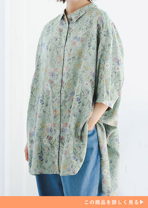ライトグリーンの花柄シャツにデニムパンツを履く女性