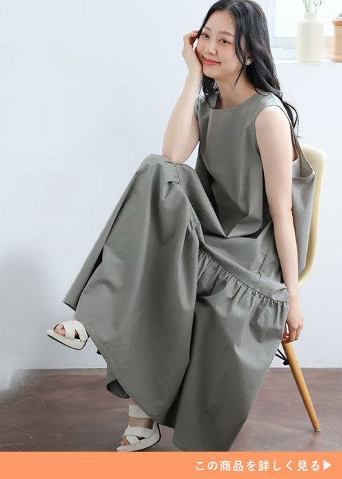 カーキのノースリーブワンピースにホワイトのサンダルを合わせる女性