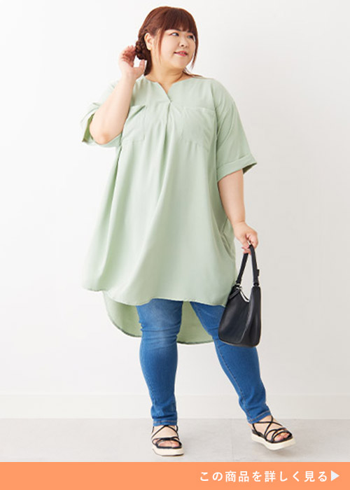 ミントのロングチュニックとデニムパンツのコーデにブラックのサンダルとバッグを合わせる女性