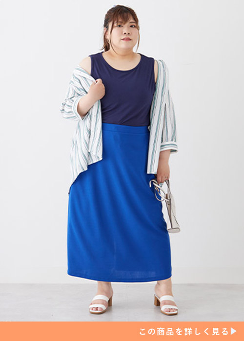 ネイビーのタンクトップとブルーのスカートにストライプシャツを羽織る女性