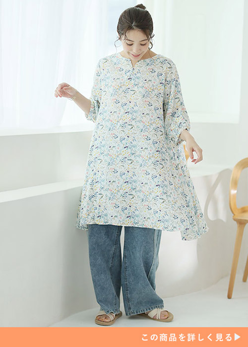 ホワイトベースの花柄チュニックとデニムパンツのコーデにサンダルを履く女性