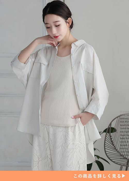 ホワイトのリブトップスと花柄ホワイトパンツのコーデにグレージュのワークシャツを羽織る女性